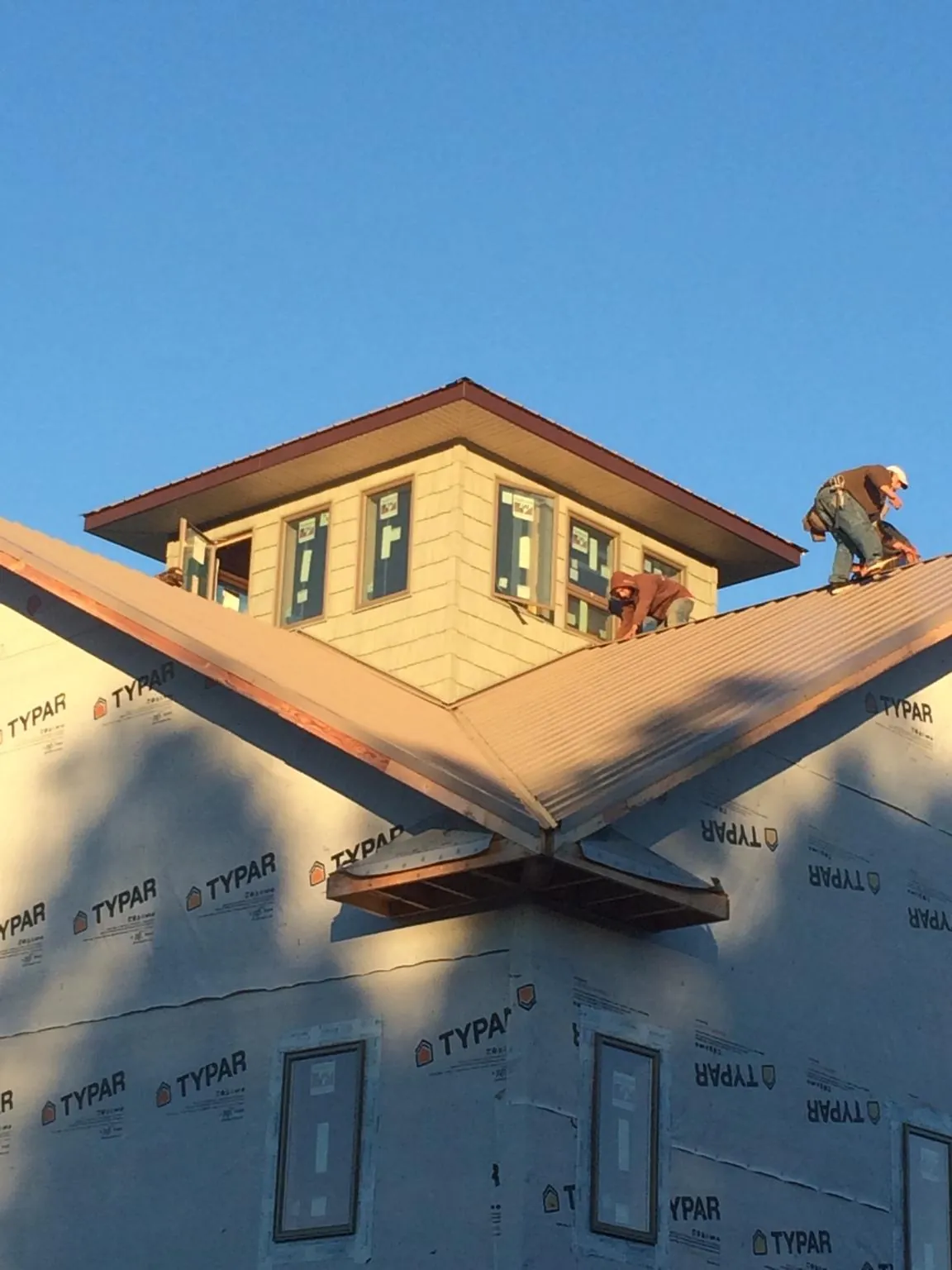Roofers working around a rooftop cupola on a new metal roof at sunset — Roof Waterproofing in Salisbury by Roofing Brothers